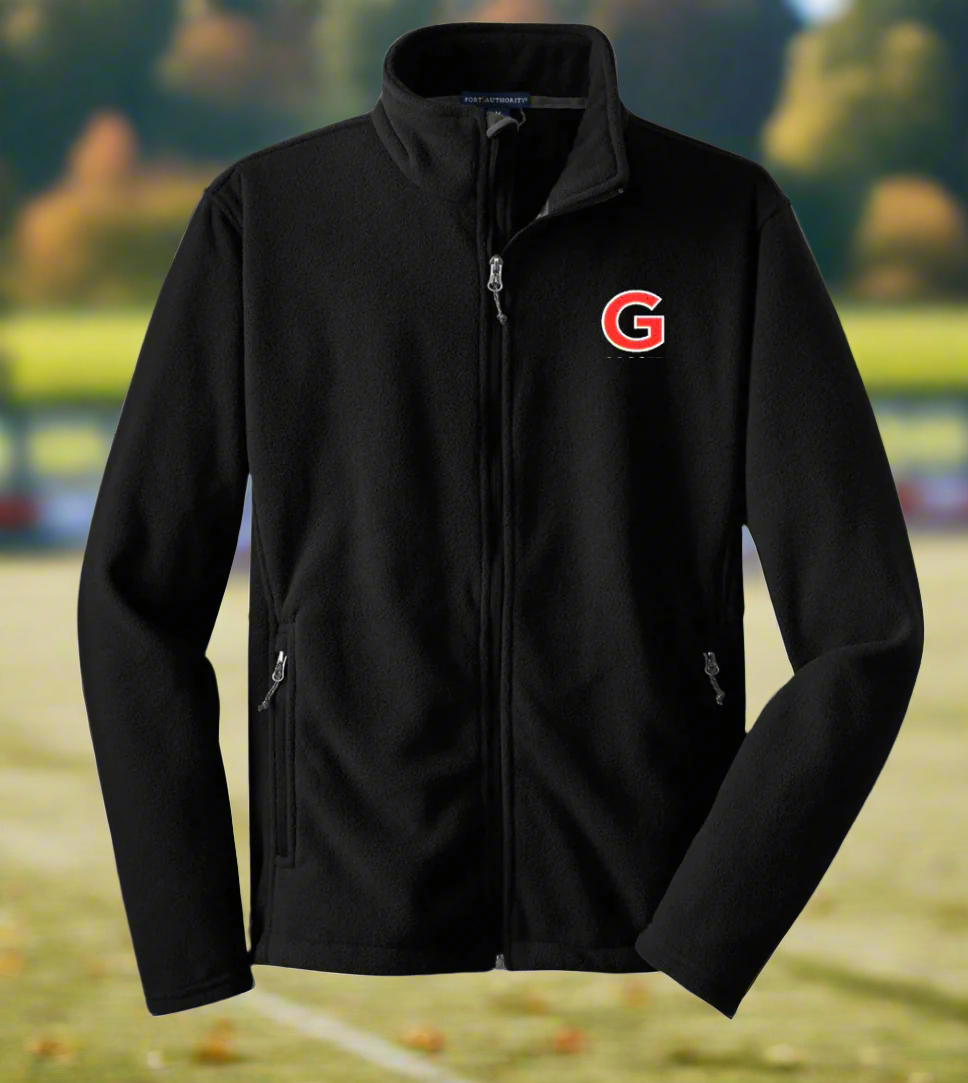 A black fleece jacket with a red logo on the chest, showcased in a winter landscape with snow-covered trees in the background.